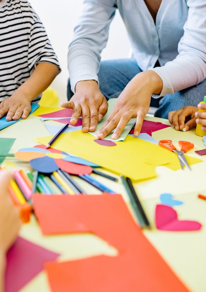 Infants i adults fent un taller de manualitats amb cartolines de colors